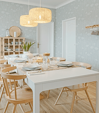 Sala de refeições com papel de parede verde, com um cabide de madeira, mesa de cozinha e candeeiros estilo natural